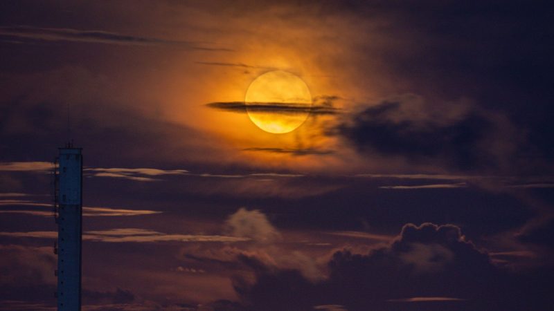 Cloudy dark orangish sky with bright full moon.