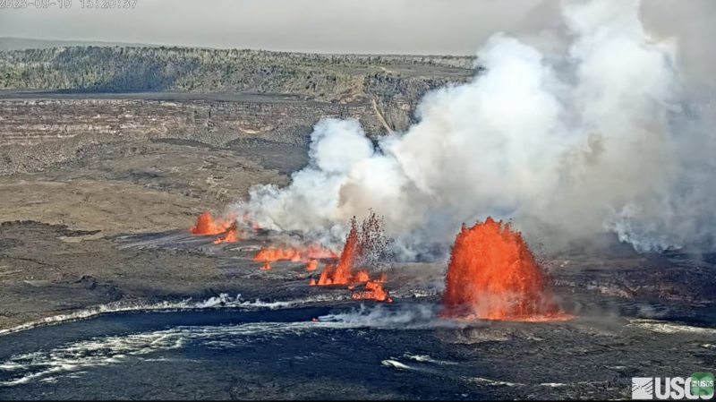 Leaping fountains of orange fire erupting from lava in a crater. Billowing white smoke.