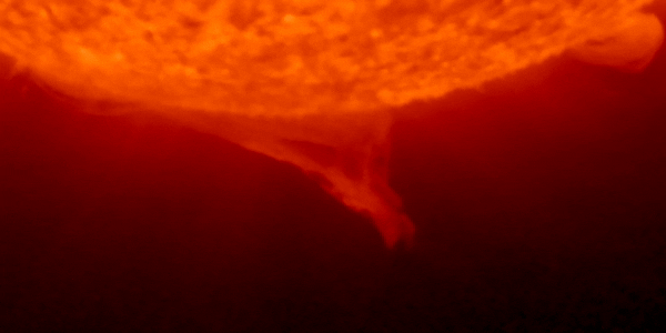The bottom part of a red sun over a black background shows prominences moving.