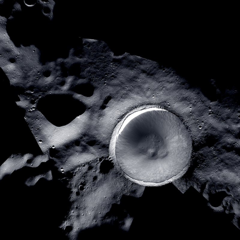 Ice on the moon: Large circular depression with bright rim on dark gray, shadowy terrain.