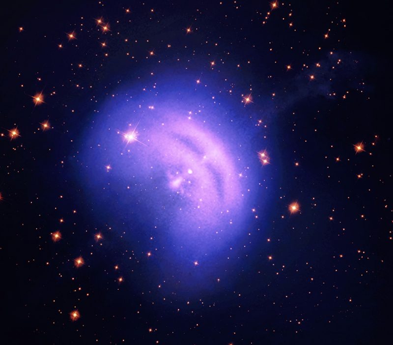 Nube espacial brillante y borrosa en forma de frijol azul y púrpura con un fondo estrellado oscuro.