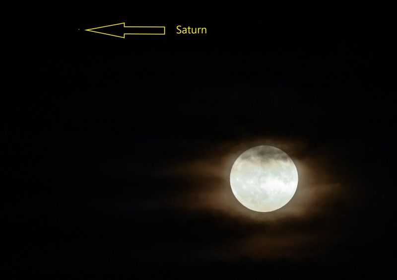 Moon somewhat covered with haze, and labeled arrow pointing to dot of Saturn nearby.