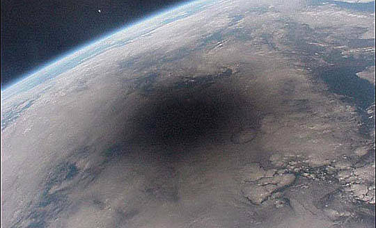 Solar eclipses: A section of the Earth from space with a dark round shadow on part of the globe.