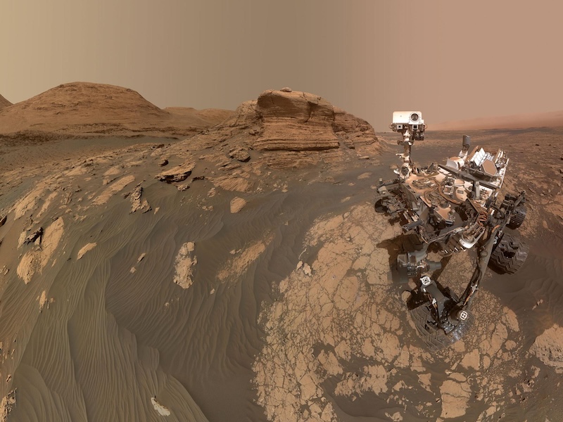 Life-supporting rivers for Mars: Mechanical rover-type vehicle sitting on brownish rocky ground on Mars with cliffs in the background.