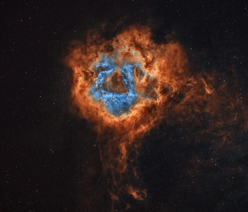 Ring of swirly orange clouds around ring of similar blue clouds in field of stars.