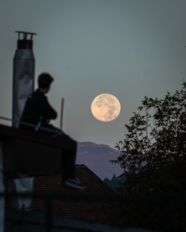 Hunter's moon: A man sits and watches the full moon set.