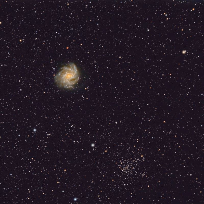 Star field with a bright spiral galaxy and a loose bunch of dozens of stars to the lower right.