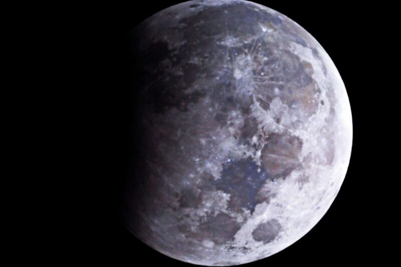 A moon with subtle colors and the left side is darkened.