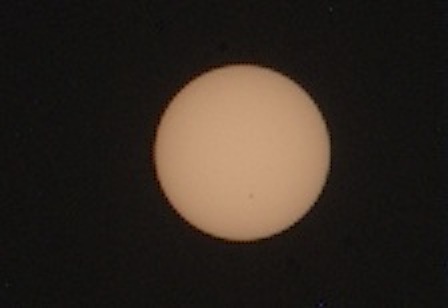 Dim, tan-colored sphere with faint dark spot visible.