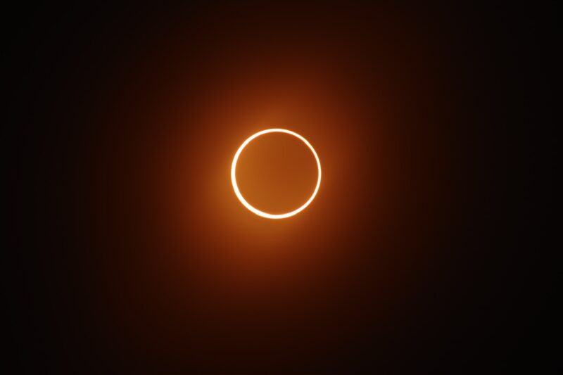 Black circle with an orange ring around it. There is an orange haze around both.