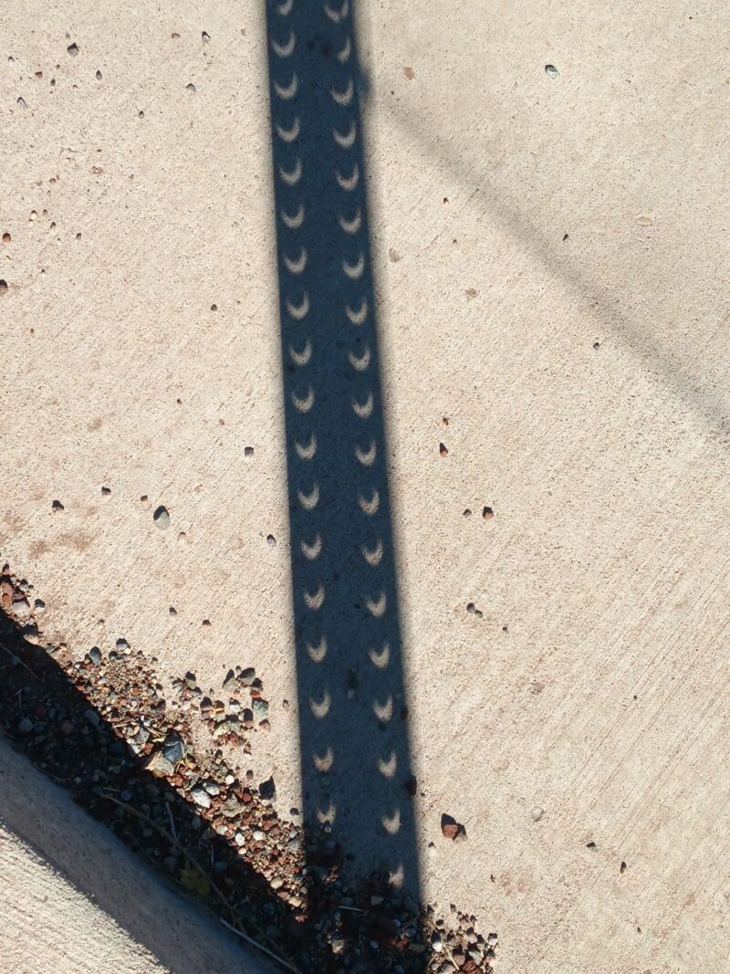 A shadow with the shape of a ruler in the floor. There are 2 bands of tiny crescents in the shadow.