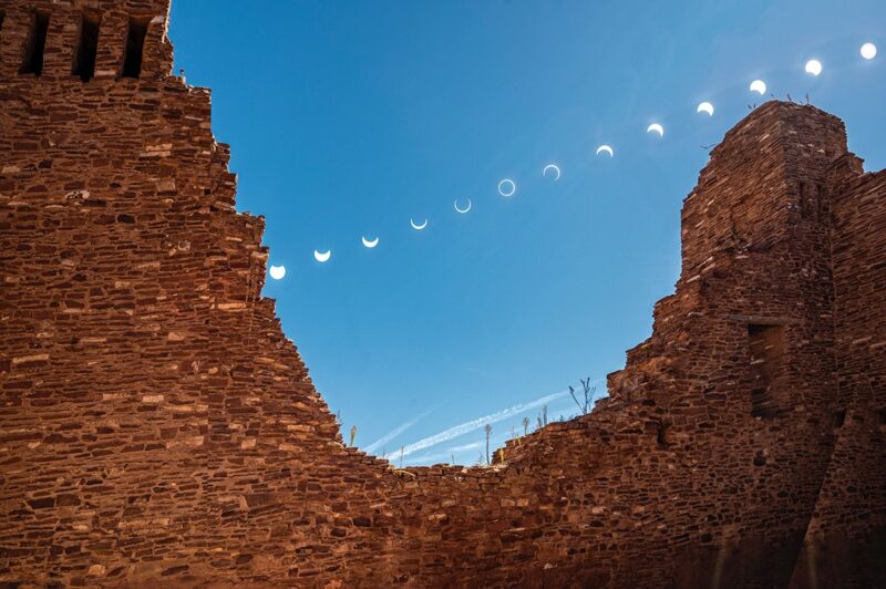 Wall of bricks in the foreground with a big hole in the middle. Different shapes for the eclipse are located in the middle of this hole.