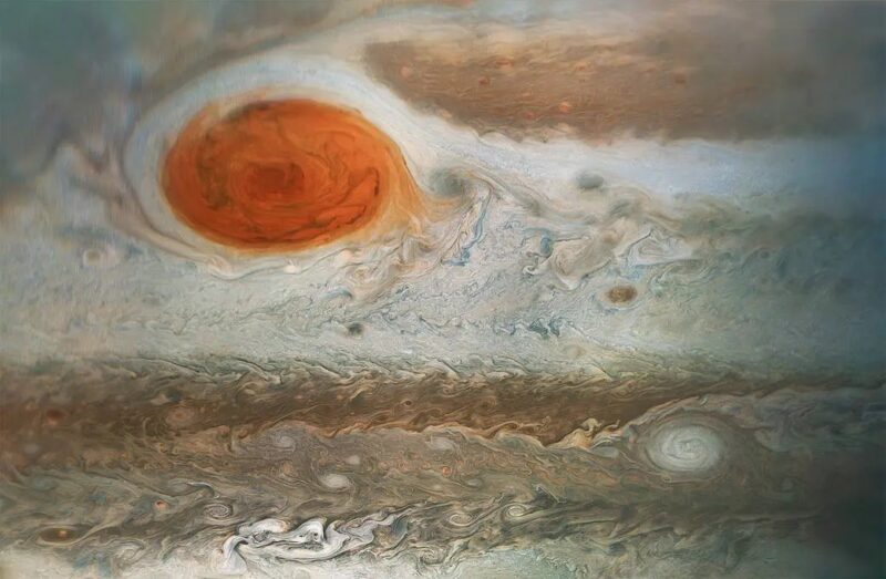 Closeup of a swirling orangish storm with white and tan whorls all around.