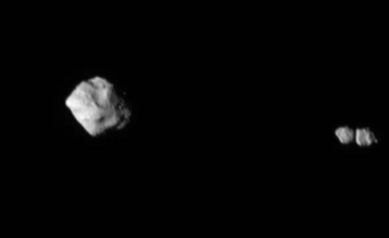 A larger, lumpy gray asteroid on the left and 2 small, abutting asteroids on the right, in black sky.