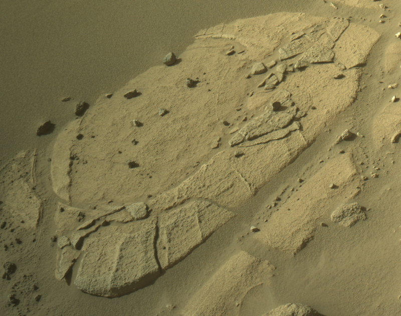 Rock features on Mars: Roundish rock formation with smaller bits of rock and stones on and around it.