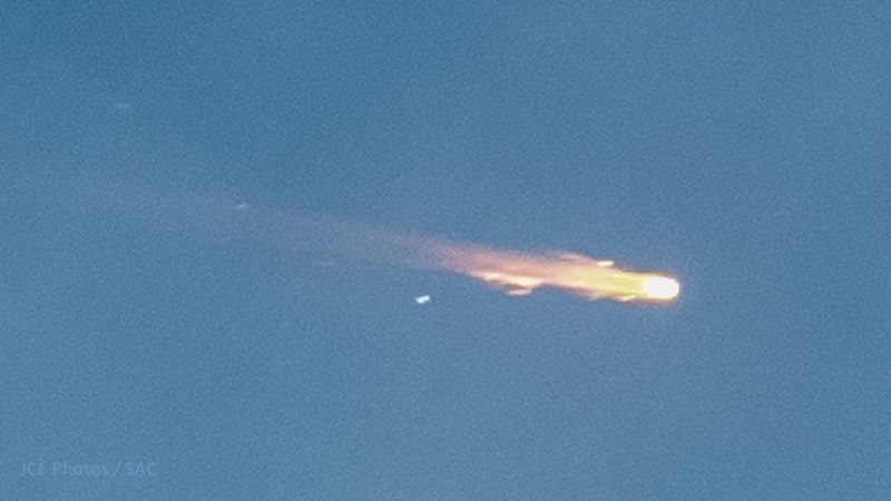 Closeup image showing a fiery breakup with a streaming tail in a blue sky.