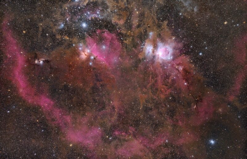 Prolific clouds of bright red nebulosity, including an arc, in a dense star field.