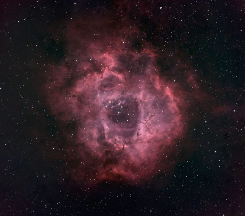 Reddish, wispy doughnut-shaped nebula in a scattered field of faint stars.