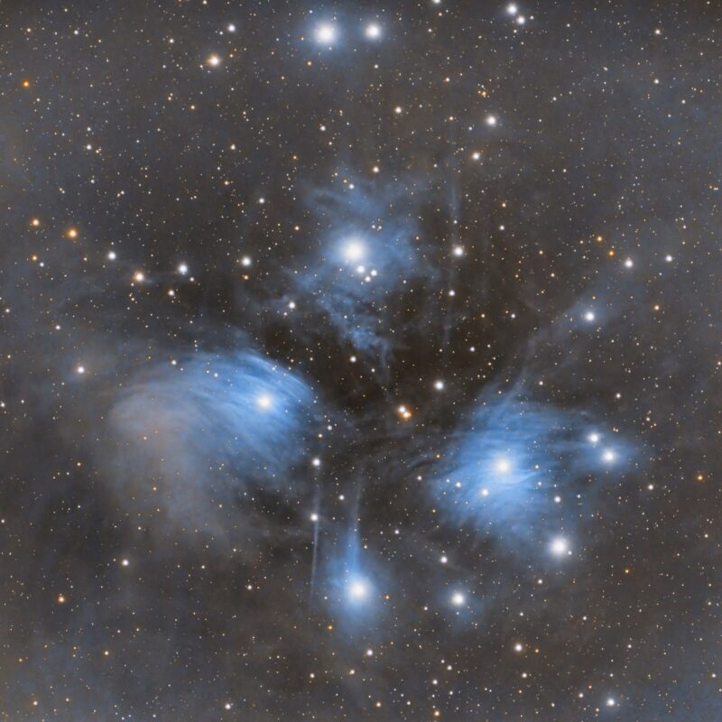 Large area of wispy blue cloudiness with bright stars embedded, in star field.