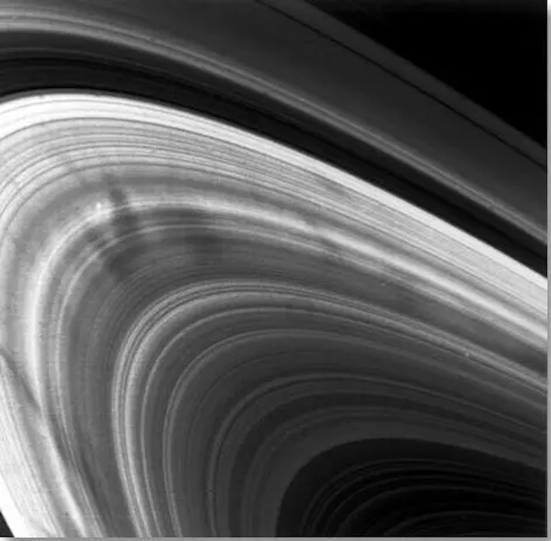 Dozens of bright and dark concentric lines curving in an arc, with dark, elongated smudges on them.