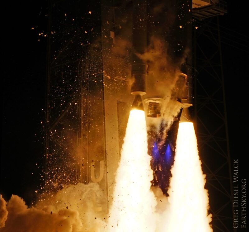 Rocket engines shooting out glowing white cones of fire and smaller blue flames, with rocket above.