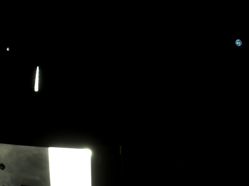 Mostly black image, with bright spacecraft parts at bottom, and distant view of small blue Earth and even smaller moon.