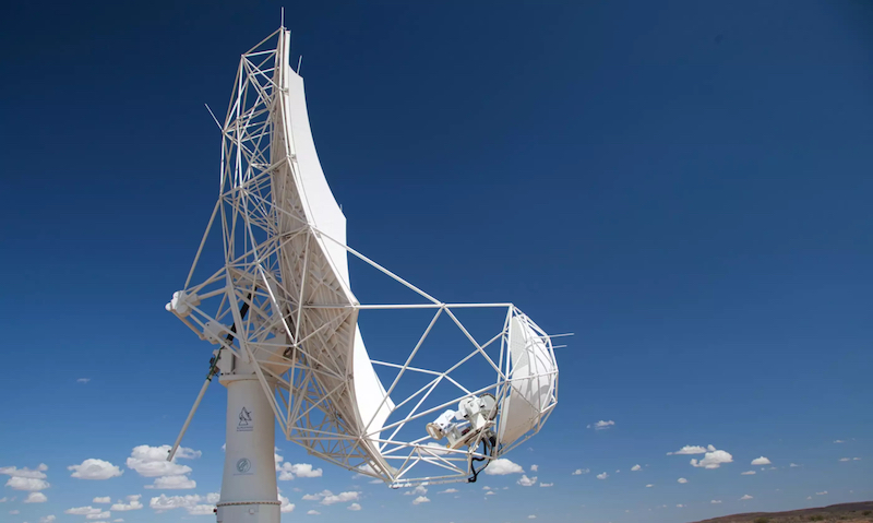 La primera luz del SKA: un telescopio blanco con forma de plato contra un cielo azul con pequeñas nubes esparcidas debajo.