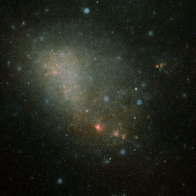 Small Magellanic Cloud: A misty patch of stars with an irregular shape, plus some brighter blue and red spots to the lower right.