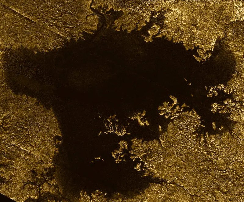 Orbital view of a dark body of liquid with branching, golden land formations that break off into the liquid.