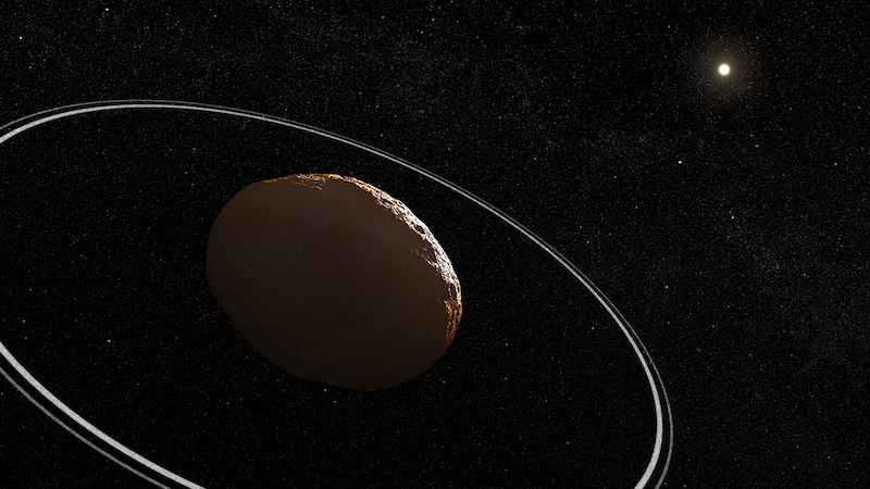 Dark egg-shaped rocky body in space, surrounded by 2 thin, bright rings, with bright star in distance.