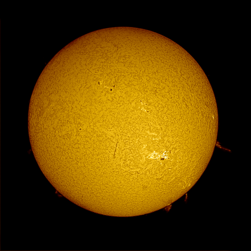 The sun, seen as a large yellow sphere with a mottled surface and dark spots.