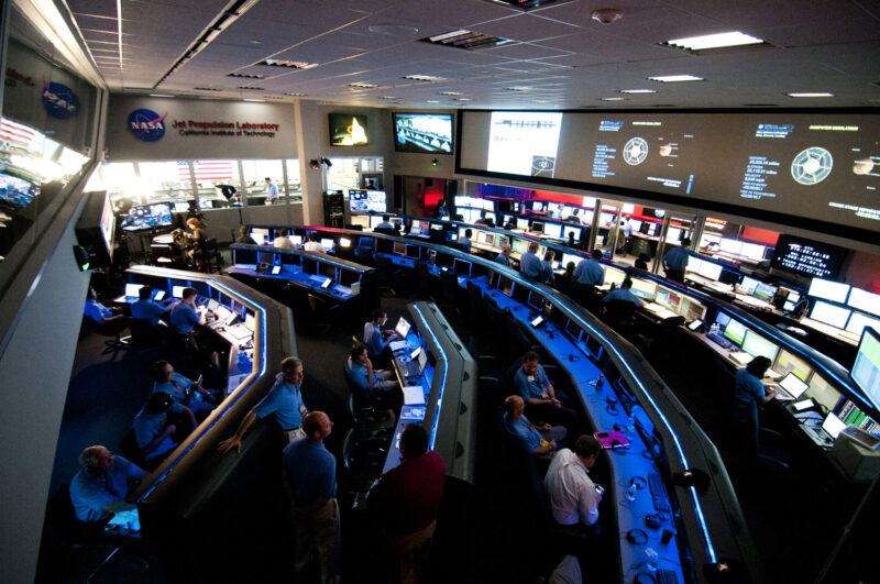 Jet Propulsion Laboratory: Large, high-ceilinged, semi-dark room with 5 long, arc-shaped ranks of computers.