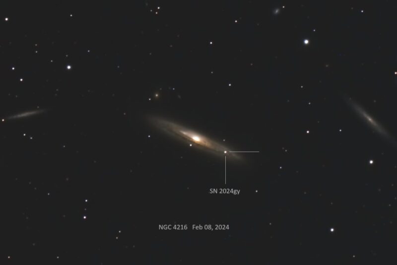 A nearly edge-on spiral galaxy with a bright point of light out to the right in the spiral arm.