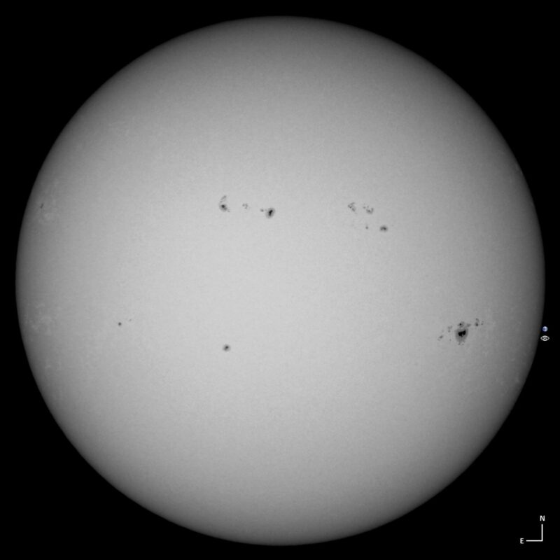 Sun news: The sun, seen as a large white sphere with small dark spots.