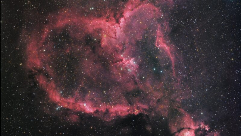 A red heart shape made of gas and dust with scattered stars.