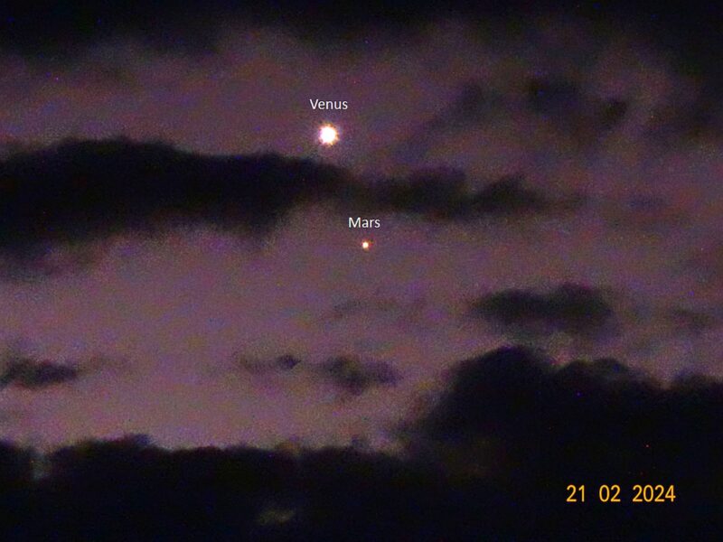 Purple-pink sky with dark clouds. A glowing white dot at the top, and a smaller reddish dot under it, both labeled.