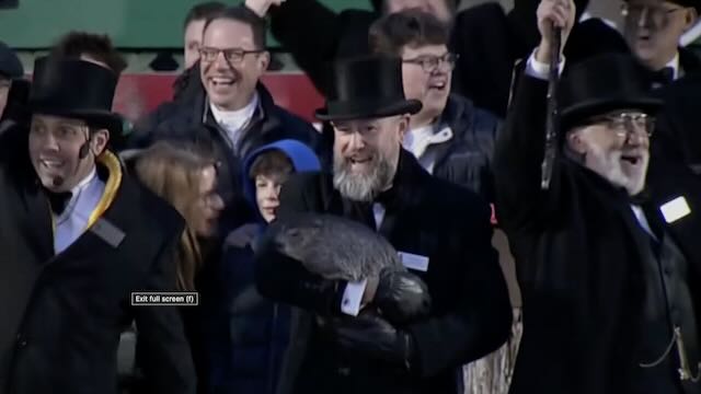 Men in top hats and tails, holding a groundhog and looking happy.