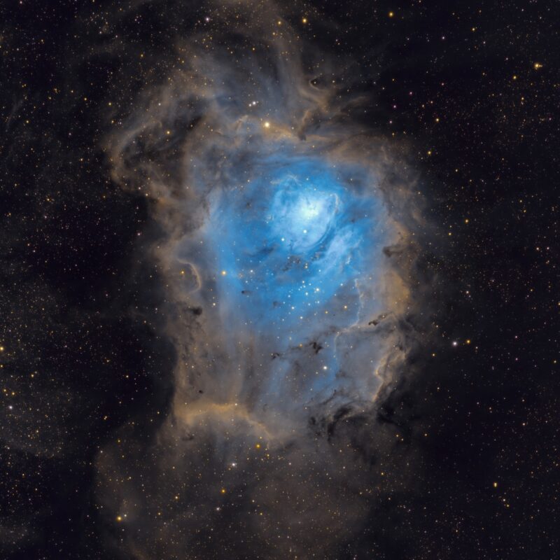 Large, bright blue cloud of gas over a multitude of distant stars.
