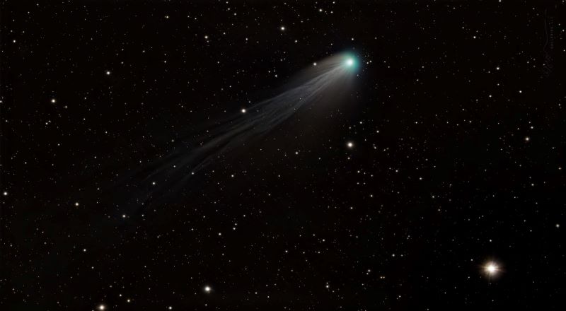 Comet Pons-Brooks with an intricate tail streaming toward the lower right.