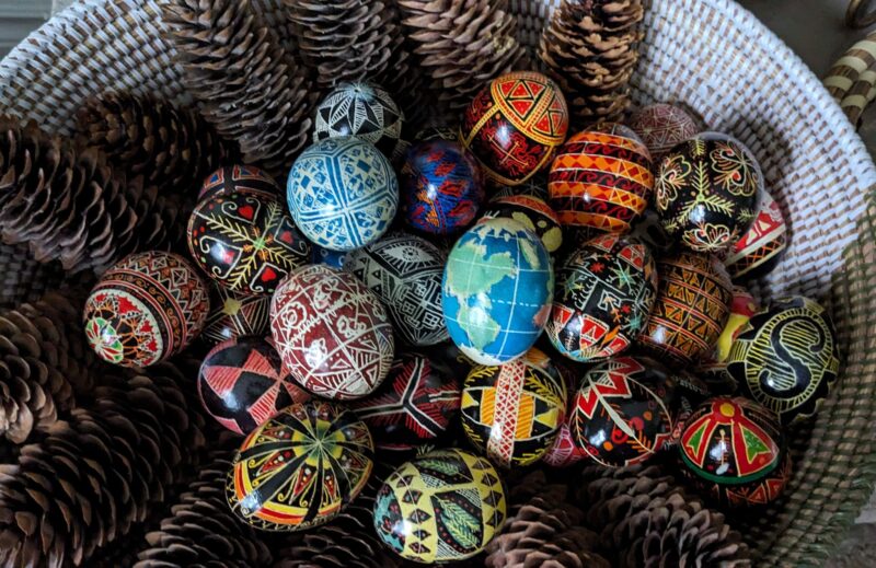 Image shows a basket full of eggs painted with colorful designs.
