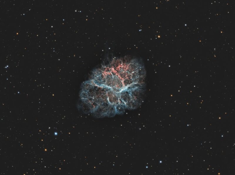 Capullo de gas azulado contra remolinos nebulosos rojos y un fondo de estrellas débiles.