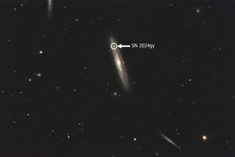 Very oblique, large yellowish spiral with a bright star shown inside a circle, and faint foreground stars.