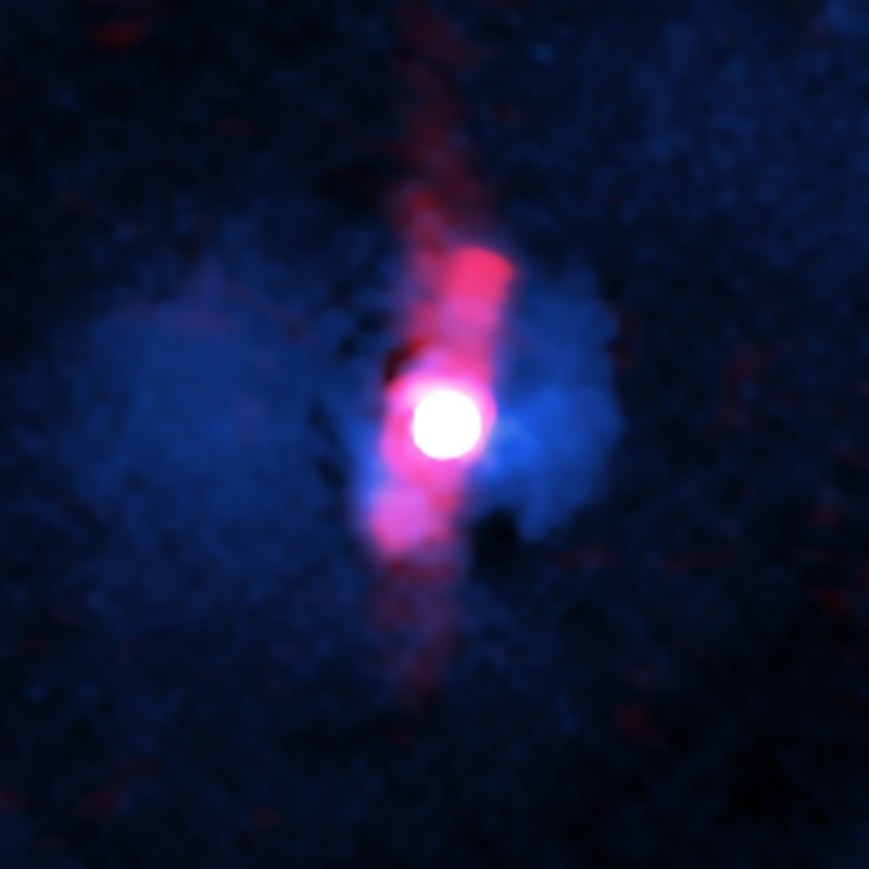 Bright white round spot with bluish and reddish blurry shapes around it on black background.