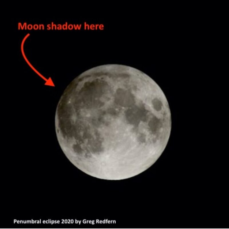 Full moon with a lightly darker area at top left and an arrow pointing to the dark area.