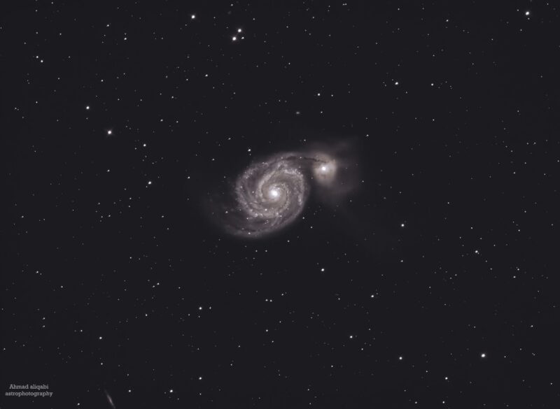 Large, whitish galaxy, a spiral seen head-on, over a multitude of distant stars.
