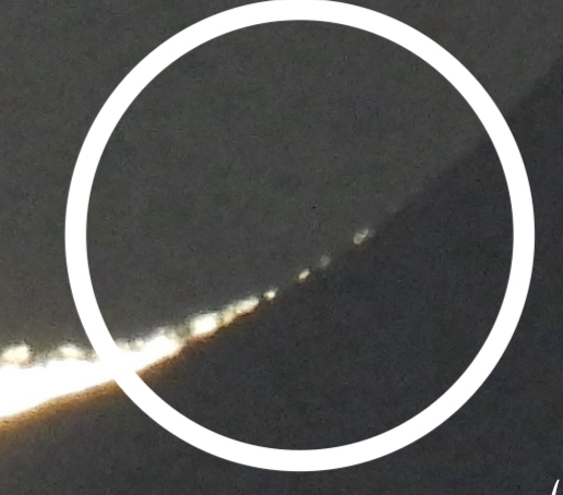 Very closeup view of tip of glowing crescent, with a row of dots extending from it.