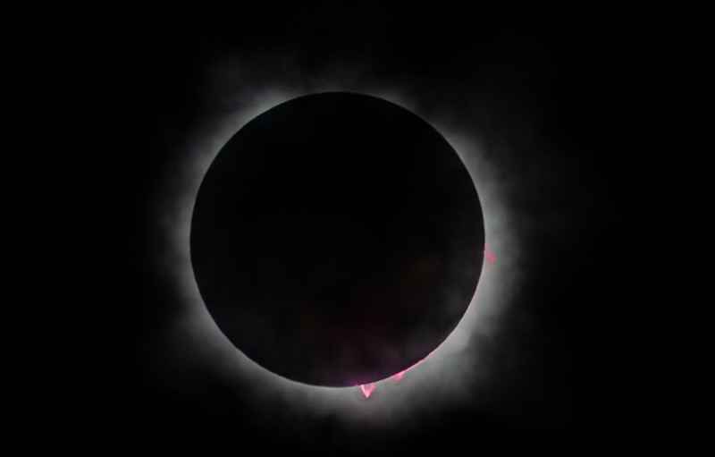 Black circle with a white halo around. There are some pink flares coming out at the right and bottom.