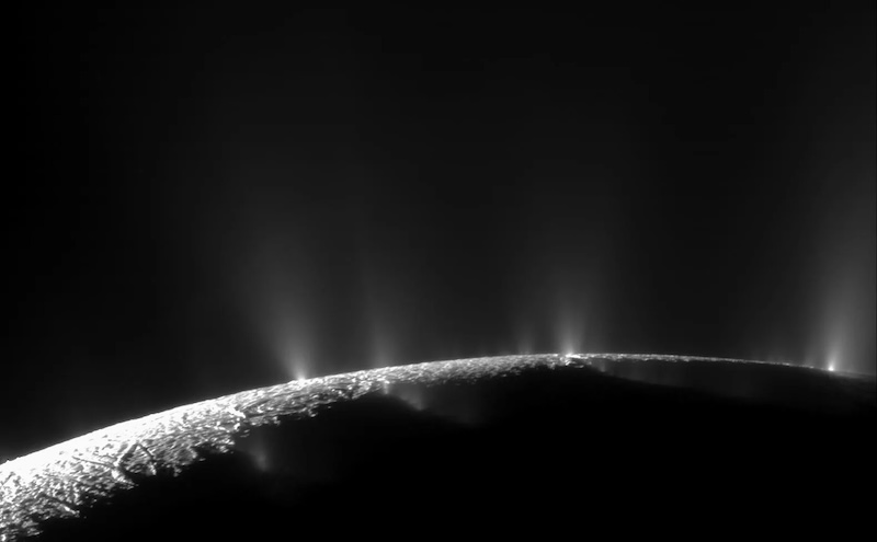 Sunlit edge of planet-like body with geyser-like jets erupting into space.