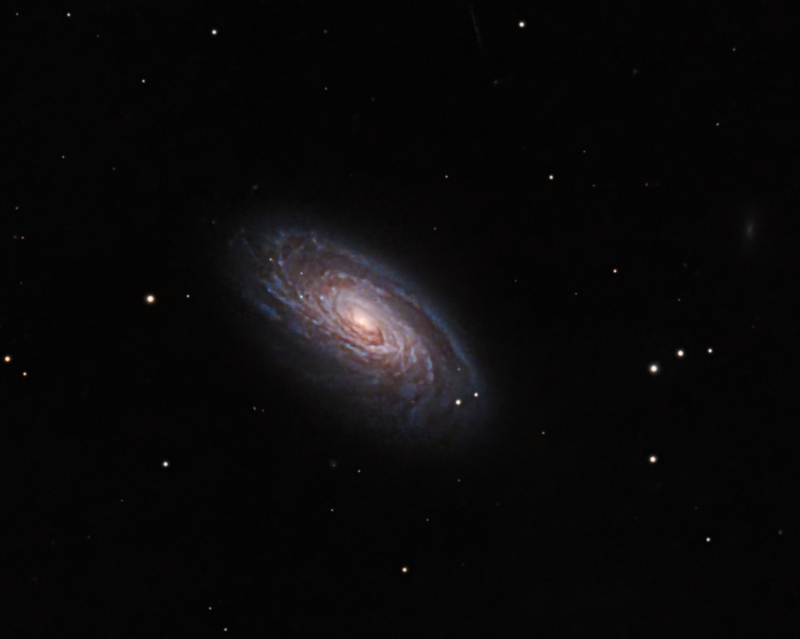 Large spiral seen sideways, with a yellowish nucleus, blue arms and sparse foreground stars.