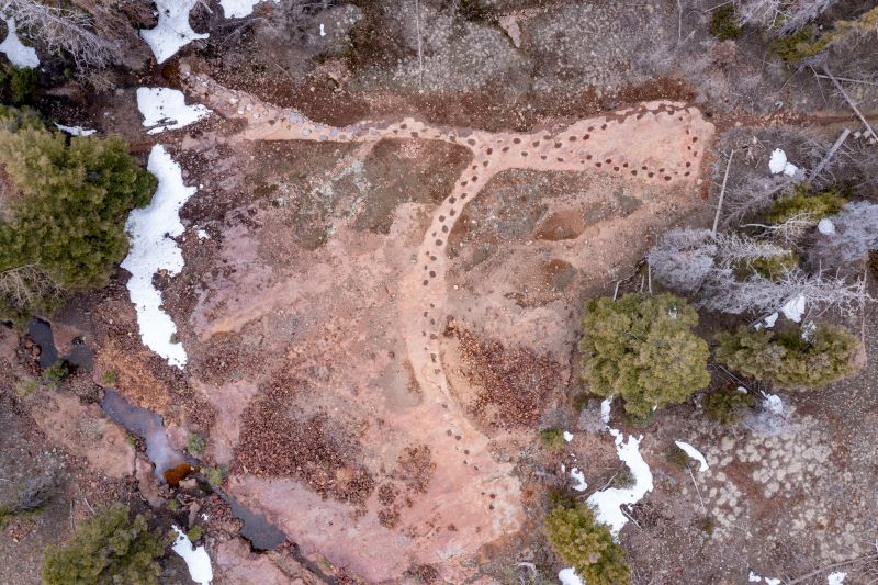 Dinosaur tracks: A drone view of mostly dry land with 2 rows of circular impressions making a loop.